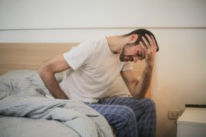 Man sitting next to bed with head hurting