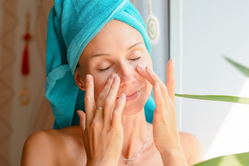 Closed eyes women touching face after shower