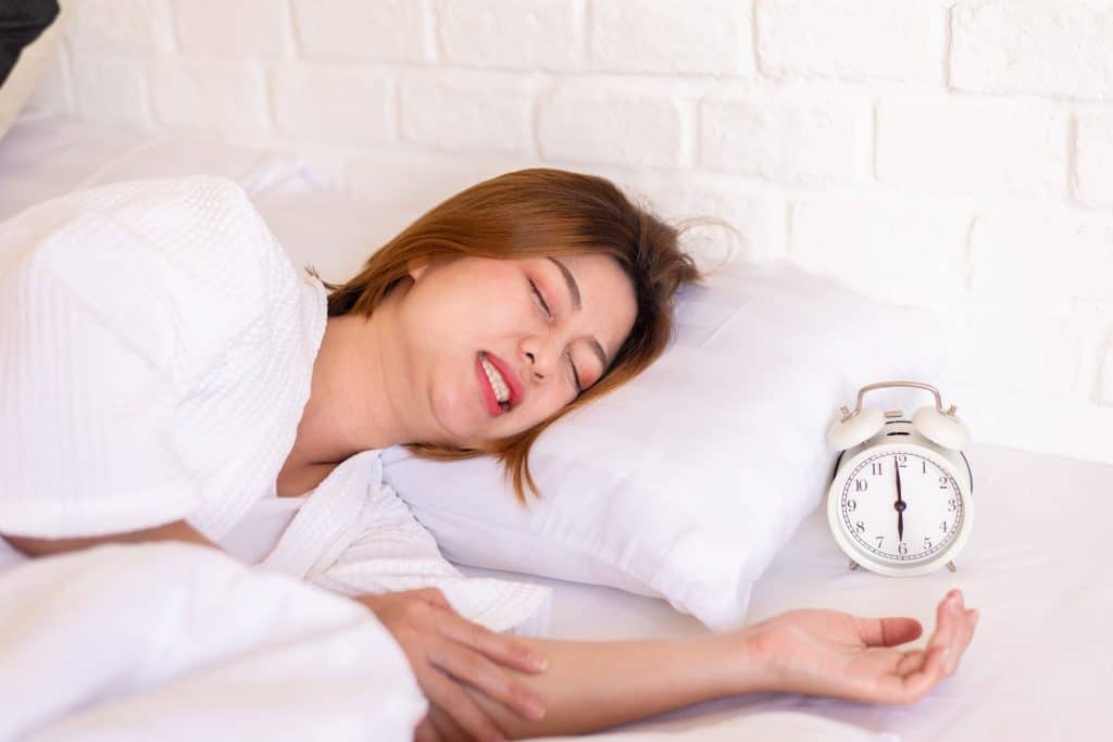 women sleeping next to alarm clock