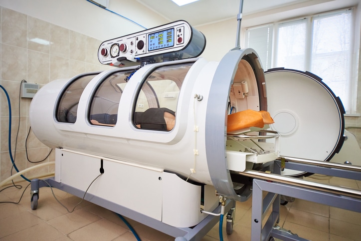 a girl in a black T-shirt lies in a hyperbaric chamber, oxygen therapy, a medical room